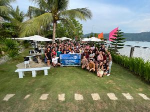 A vibrant beach snapshot featuring a group of people striking a pose, enjoying a summer day during a TMJP BPO company gathering.