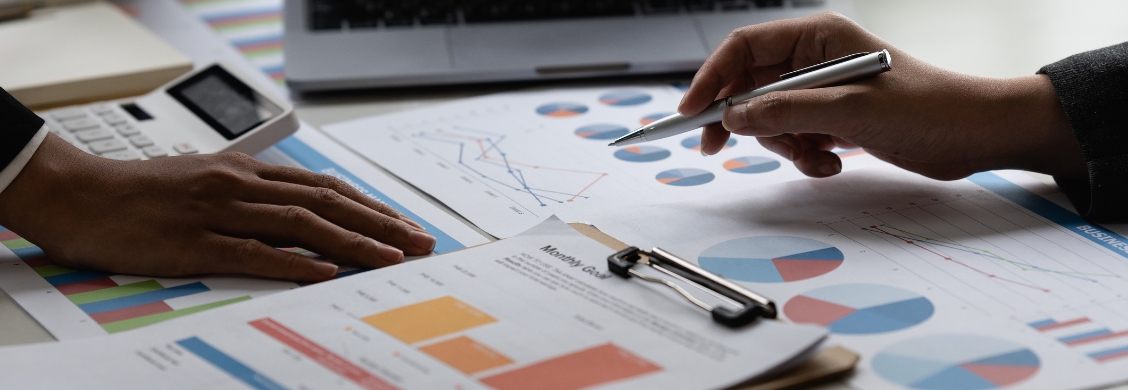 Business people analyzing data and documents in a back office, focusing on graphs and papers.