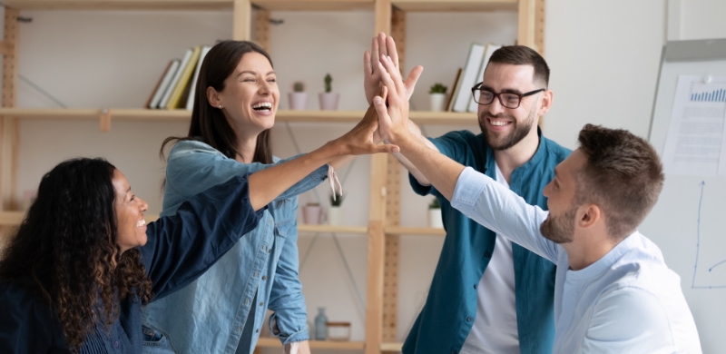 A group of people celebrating success and showing camaraderie by giving high fives to each other.