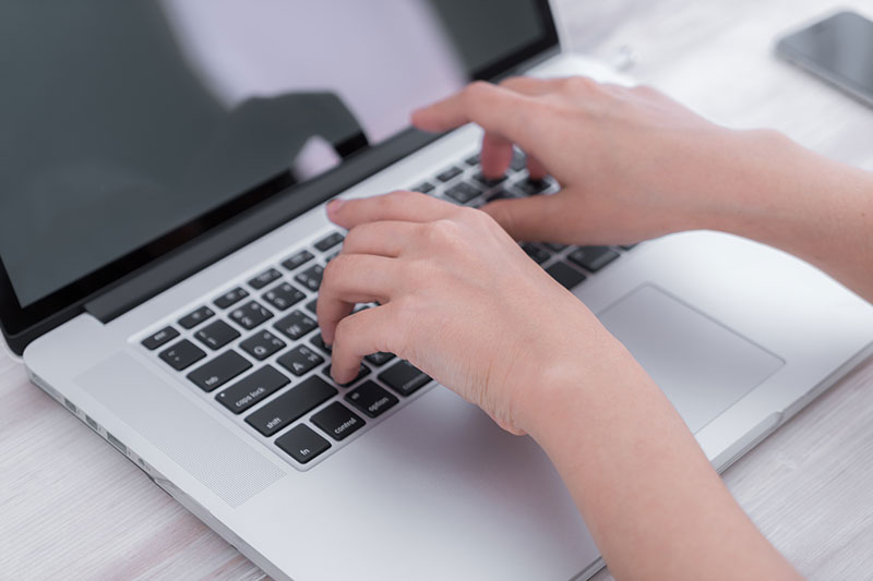 A person typing on a laptop, improving customer experience.