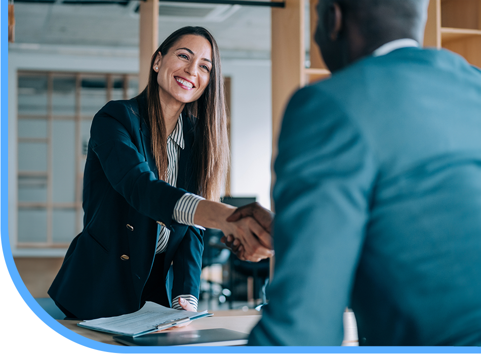 A professional woman shaking hands with another woman in an office, symbolizing positive customer experience.