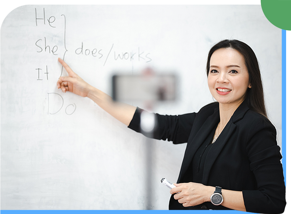 An online English learning session with a woman in a business suit pointing at a whiteboard.
