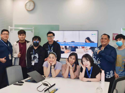 A group of people happily posing for a photo in front of a large screen at a BPO company in BGC Taguig.