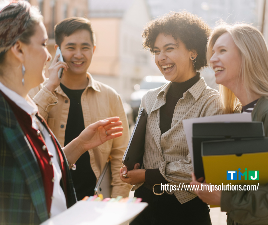 Four professionals standing outdoors, conversing with documents and a phone, symbolizing Business English as a tool for building stronger global teams.
