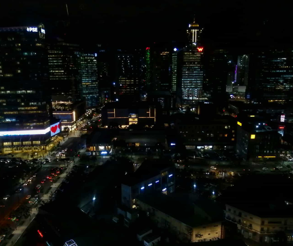 Night view of Bonifacio Global City (BGC) skyline with illuminated buildings, busy streets, and bright city lights as seen from the TMJP office.