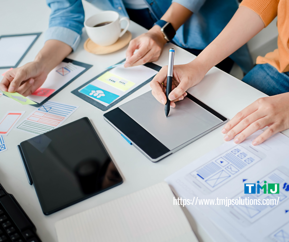 Team collaborating on wireframes and tablet during a design session, symbolizing secure and scalable digital platforms built through outsourcing.