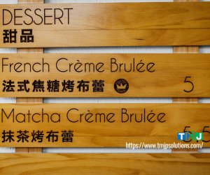 A wooden restaurant signage with menu in two languages