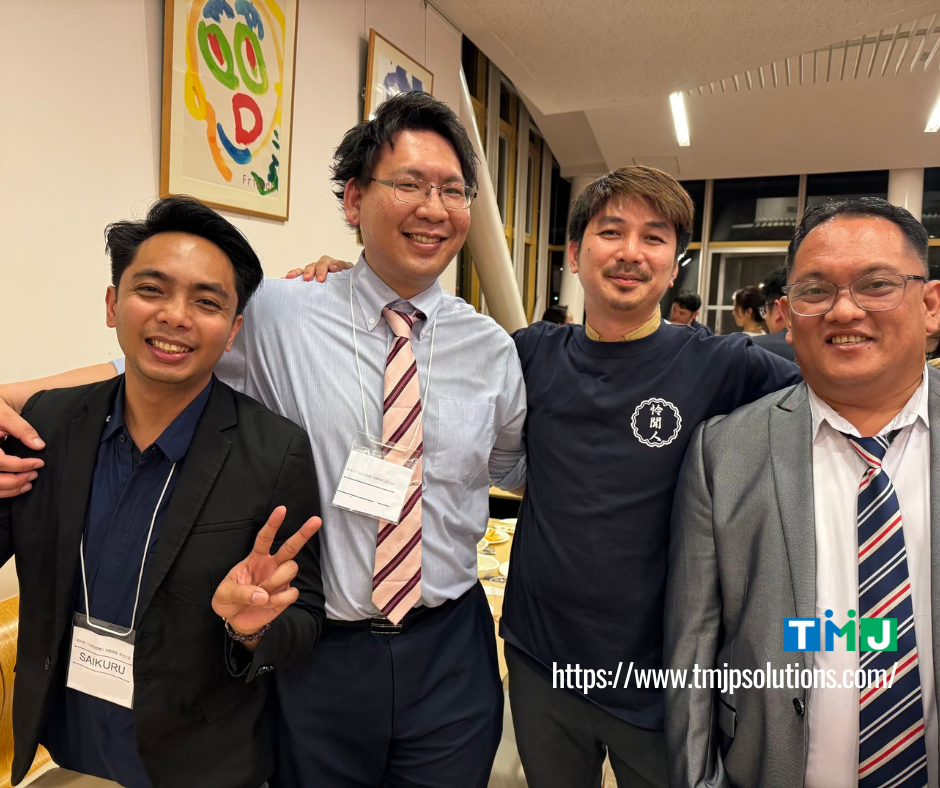 Four individuals standing together at a professional event, three TMJP QC Circle members with name tags and one representative from TMJ, captured during the 2024 Kaizen convention in Japan.